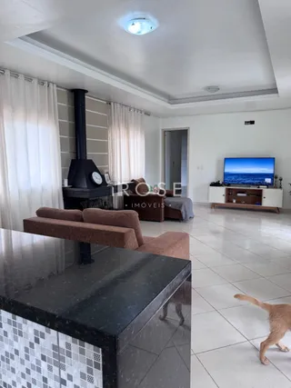 Sala de estar com cortinas brancas e piso de cerâmica.