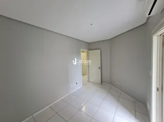 Corredor interno com piso de cerâmica claro.
