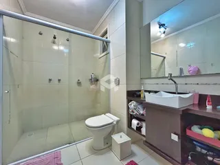 Foto de um banheiro com box de vidro e azulejos claros.
