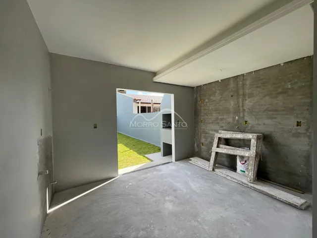 Interior com paredes de concreto aparente e acesso a um jardim externo.