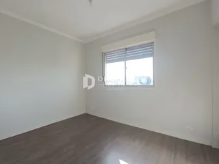 Ambiente interno de uma sala com piso de madeira clara e janela.