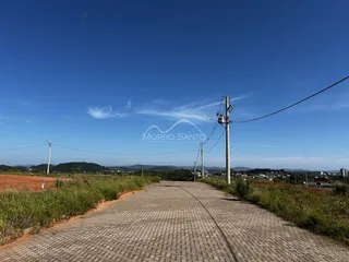 Uma estrada pavimentada se estende por uma paisagem rural com colinas ao fundo.