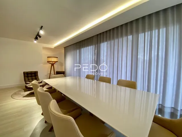 Sala de jantar com grandes janelas e cortinas claras.
