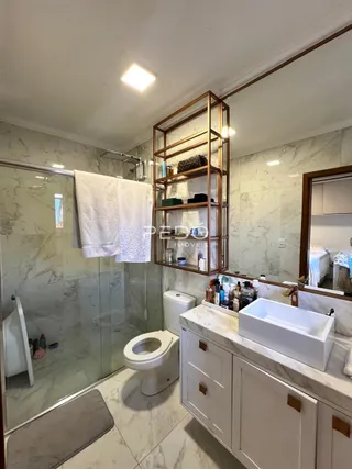 Foto de um banheiro com box de vidro e louças brancas.