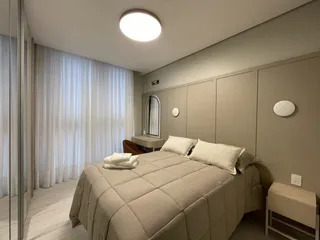 Quarto com cama e cortinas brancas em um ambiente claro.