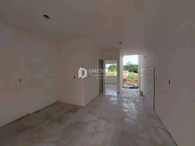 Interior de um espaço amplo com paredes brancas e piso de concreto.