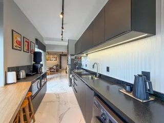 Vista da cozinha moderna com armários escuros e piso de mármore.