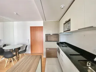 Ambiente interno mostrando uma área de jantar adjacente a uma cozinha moderna.