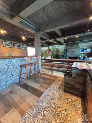 Ambiente interno com bancada de bar e piso de madeira.