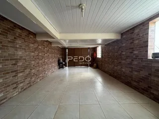 Corredor interno com paredes de tijolo aparente e piso de cerâmica.