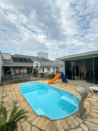Foto de uma piscina externa com escorregador em um pátio de tijolos.