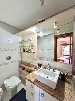 Foto de um banheiro com azulejos brancos e bancada de granito.