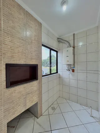 Interior de um ambiente com parede de tijolos aparentes e piso de cerâmica branca.