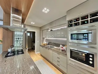 Cozinha moderna com armários cinzas e bancadas de granito em um imóvel no Brasil.