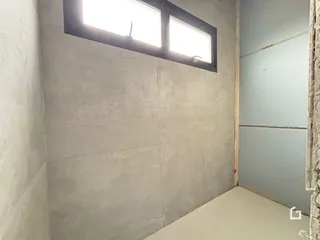 Parede interna com janela de grande porte em ambiente sem acabamento.