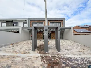 Fachada moderna de uma residência com pátio pavimentado.