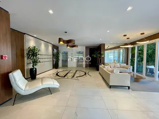 Sala de estar moderna com piso claro e grandes janelas de vidro.
