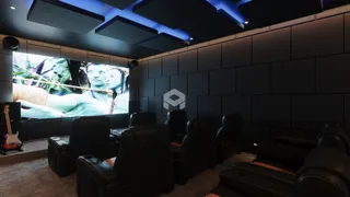 Sala de estar com assentos de couro voltados para uma tela grande.
