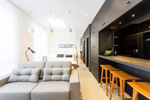 Sala de estar moderna com sofá cinza e paredes brancas.
