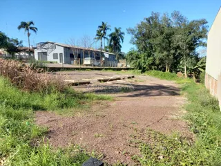 Foto da fachada de uma propriedade com terreno e vegetação ao ar livre.