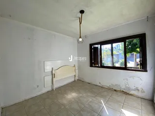 Quarto com piso de cerâmica e janela de madeira.