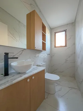Banheiro moderno com bancada de mármore e armários de madeira.