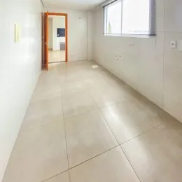 Corredor interno com piso de cerâmica e janela na parede.
