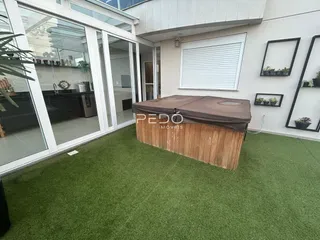 Área externa com gramado artificial e estrutura de churrasqueira em Lajeado.