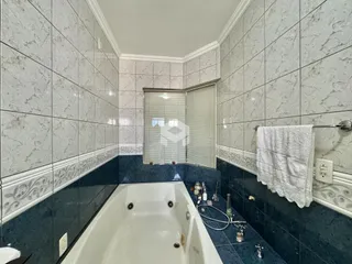 Interior de um banheiro com banheira e revestimento de azulejos.