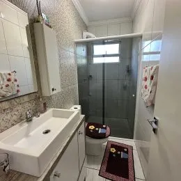 Foto de um banheiro com pia e box de vidro.