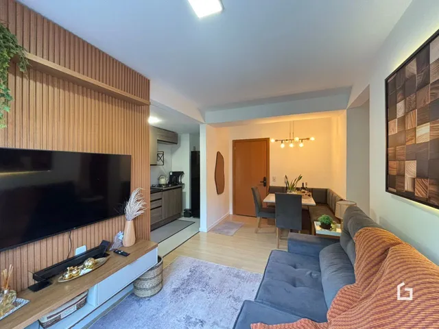 Sala de estar com televisão e área de jantar em um apartamento.