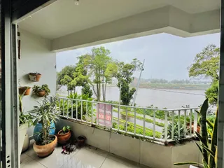 Vista da varanda com paisagem de rio e vegetação.