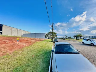 Vista externa de uma propriedade com gramado e estruturas ao fundo.
