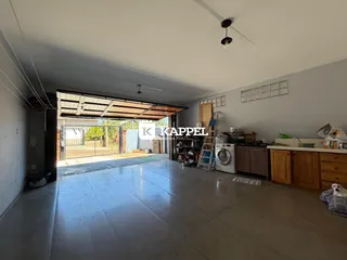 Vista interna de uma sala ampla com piso de cerâmica e acesso a uma área externa.