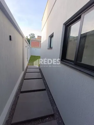 Vista externa de um corredor entre duas paredes brancas com um caminho pavimentado.