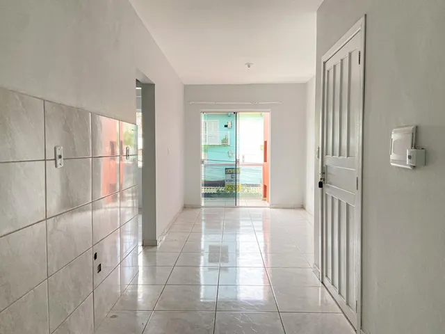 Corredor interno com piso de cerâmica e paredes brancas em um imóvel.