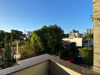 Fachada de uma residência com vegetação ao fundo sob um céu azul.