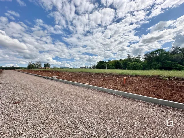 Vista de uma área aberta com campo e vegetação ao fundo.