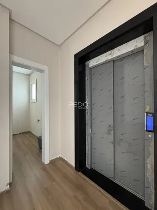 Hall de entrada com piso de madeira e porta aberta.