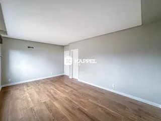 Foto de um ambiente interno com piso de madeira clara e paredes brancas.