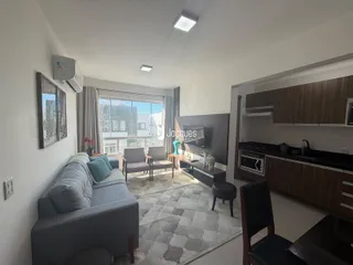 Sala de estar com sofá e vista pela janela em um apartamento no Brasil.