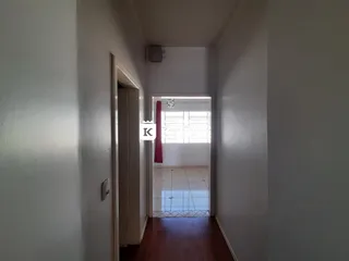 Corredor interno com piso de madeira e porta de acesso a outro cômodo.