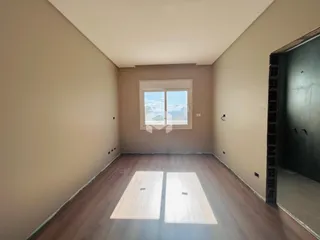 Vista interna de um corredor com piso de madeira e janela.