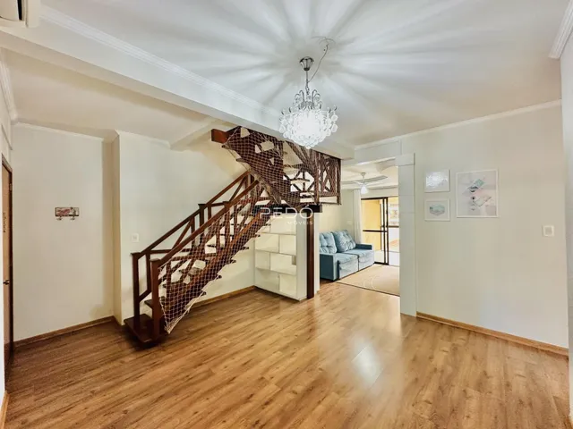 Interior de uma sala com piso de madeira e escadaria.
