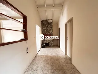 Um corredor interno com piso de cerâmica e lareira de pedra.