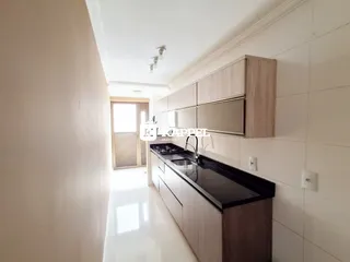 Vista de uma cozinha moderna com armários e bancada escura em um corredor claro.