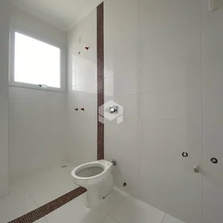 Foto de um banheiro com revestimento branco e piso claro.