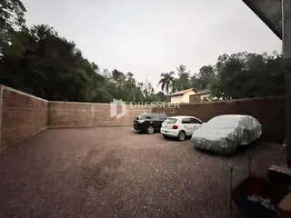 Vista externa de um terreno com carros estacionados e cerca no fundo.