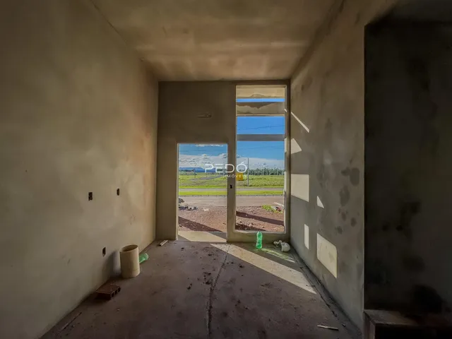 Interior de um espaço com paredes de concreto e uma porta para o exterior.