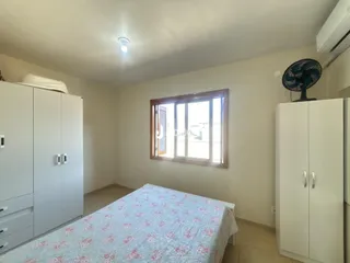 Quarto com armários brancos e janela no ambiente.